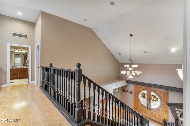 staircase featuring hardwood / wood-style floors, lofted ceiling, and a chandelier