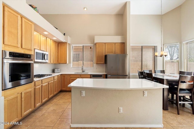 kitchen with pendant lighting, appliances with stainless steel finishes, a towering ceiling, and a center island