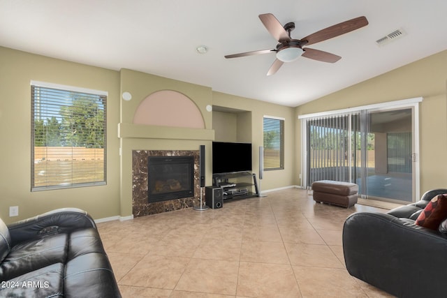 tiled living room featuring a premium fireplace, ceiling fan, and vaulted ceiling