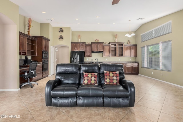 living room featuring a chandelier, light tile patterned floors, sink, and a high ceiling