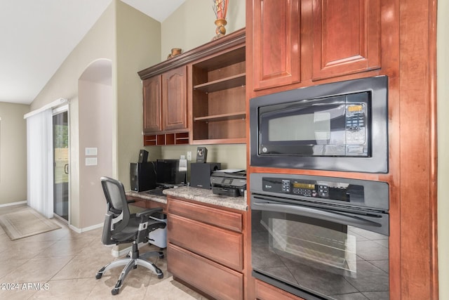 kitchen featuring lofted ceiling, black appliances, light stone countertops, built in desk, and light tile patterned flooring