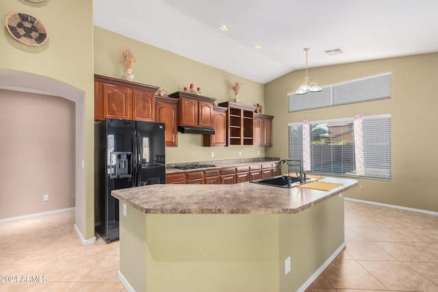 kitchen with sink, black fridge, an island with sink, stainless steel gas stovetop, and light tile patterned floors