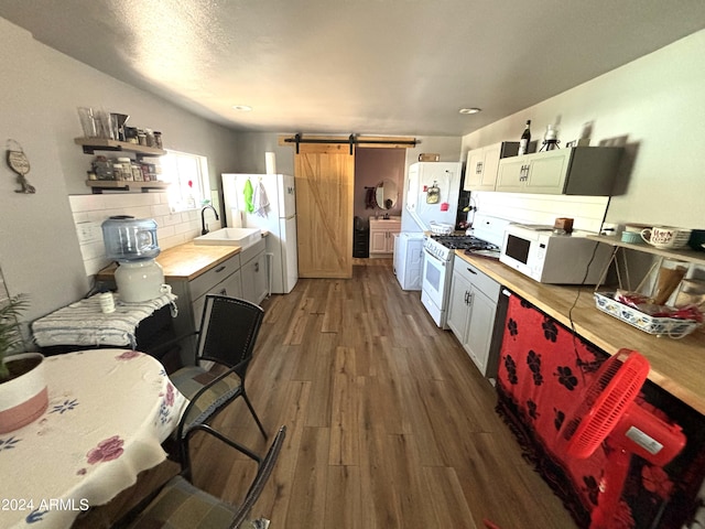 kitchen with backsplash, white cabinetry, dark hardwood / wood-style floors, a barn door, and white appliances