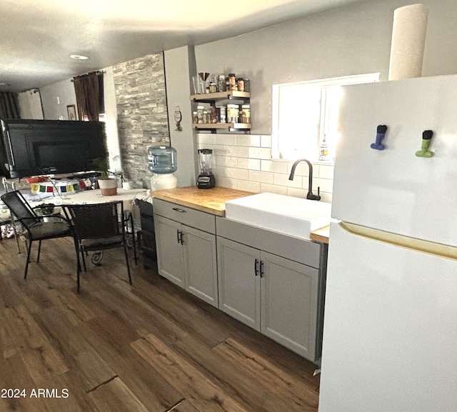 kitchen with decorative backsplash, wooden counters, dark hardwood / wood-style floors, white refrigerator, and sink