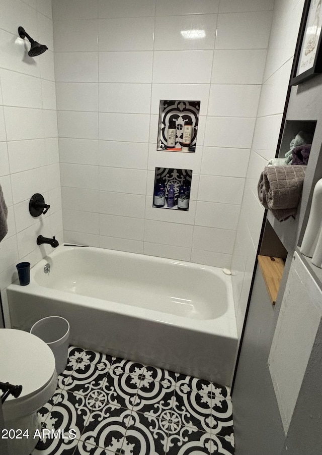 bathroom featuring toilet, tiled shower / bath combo, and tile patterned floors