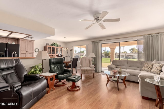 living room with ceiling fan with notable chandelier and light hardwood / wood-style flooring