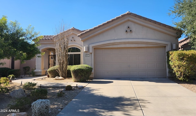 mediterranean / spanish house with concrete driveway, a tiled roof, an attached garage, and stucco siding