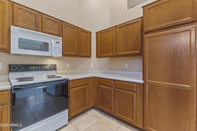 kitchen featuring white microwave, light tile patterned floors, light countertops, and range with electric stovetop