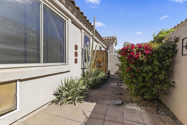 view of home's exterior featuring fence, a tiled roof, and stucco siding