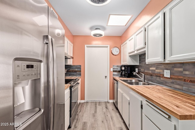 kitchen featuring a sink, tasteful backsplash, appliances with stainless steel finishes, under cabinet range hood, and light wood-style floors