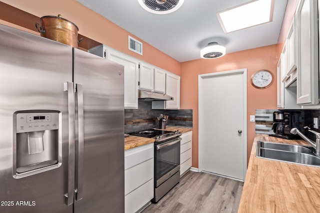 kitchen featuring under cabinet range hood, a sink, visible vents, white cabinets, and appliances with stainless steel finishes