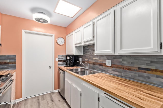 kitchen with decorative backsplash, a sink, stainless steel appliances, and butcher block counters