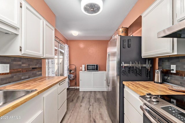 kitchen with wood counters, stainless steel appliances, ventilation hood, and visible vents