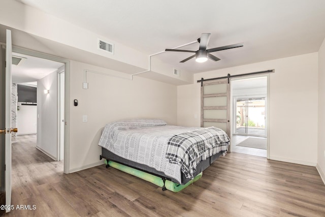 bedroom featuring a barn door, visible vents, and wood finished floors