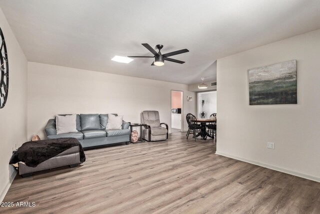 living room with baseboards, ceiling fan, and wood finished floors