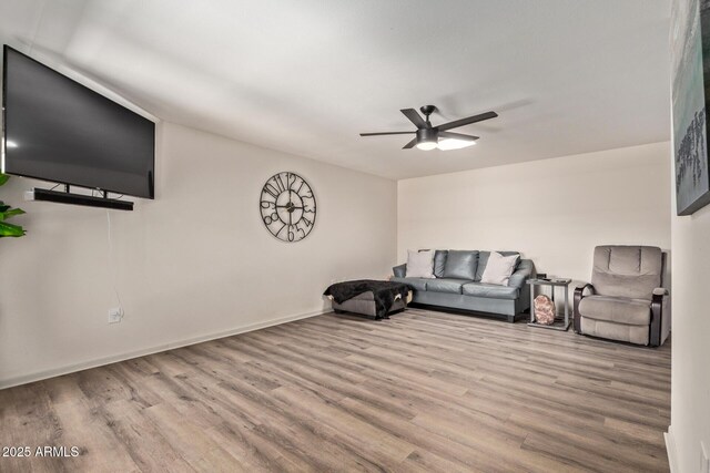 living room with a ceiling fan, baseboards, and wood finished floors