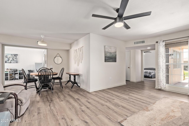 dining space with baseboards, visible vents, a ceiling fan, and wood finished floors