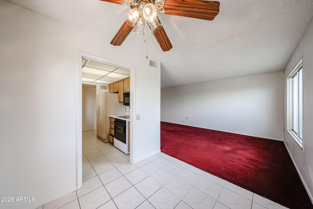 unfurnished room with ceiling fan, a textured ceiling, visible vents, light colored carpet, and baseboards