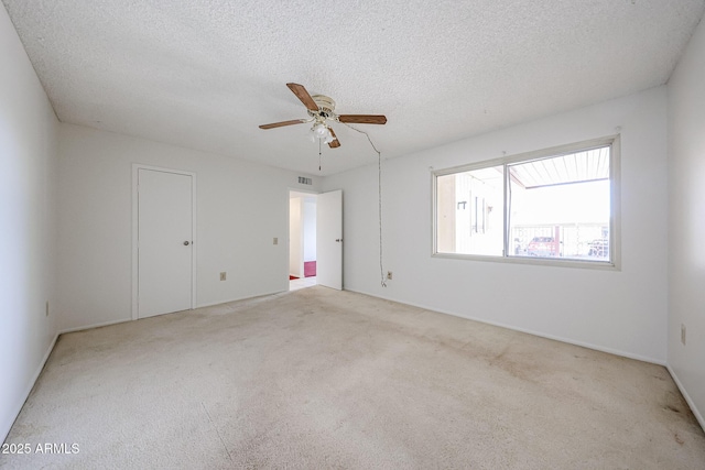 empty room with carpet floors, ceiling fan, a textured ceiling, and visible vents