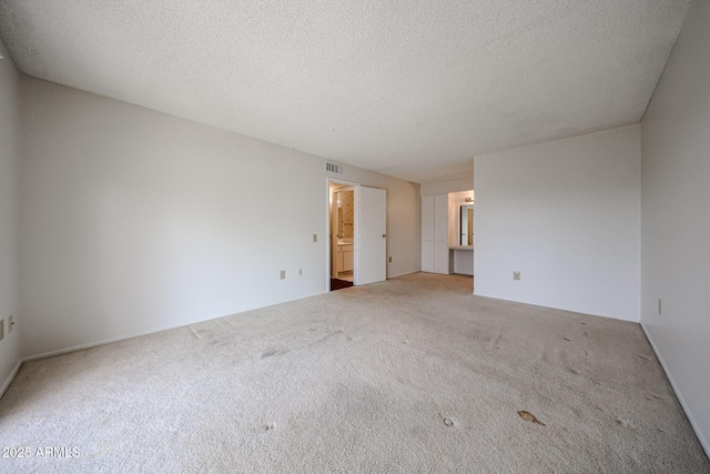 carpeted empty room featuring a textured ceiling and visible vents