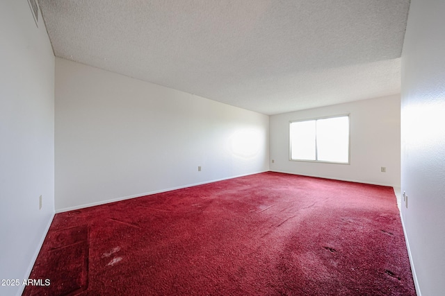 empty room featuring carpet floors, baseboards, and a textured ceiling