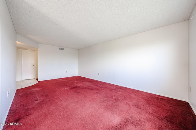 spare room featuring visible vents, a textured ceiling, and carpet