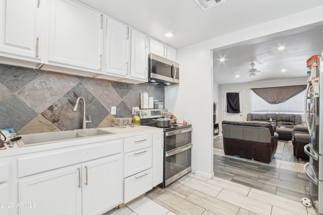 2223 E Roosevelt St, Phoenix, AZ 85006 - kitchen featuring a sink, stainless steel appliances, white cabinets, visible vents, and decorative backsplash