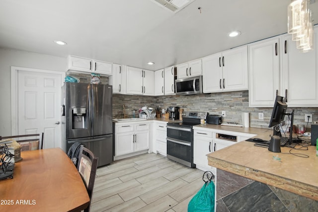 2223 E Roosevelt St, Phoenix, AZ 85006 - kitchen featuring white cabinetry, appliances with stainless steel finishes, and decorative backsplash