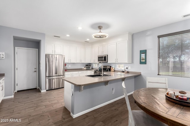 kitchen featuring white cabinets, kitchen peninsula, sink, and stainless steel appliances