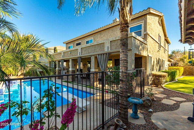 rear view of property with a patio and a fenced in pool