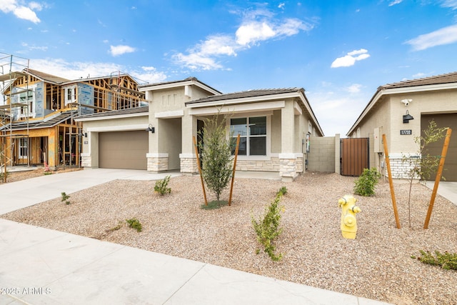 17778 W Turquoise Ave, Waddell, AZ 85355 - view of front of home featuring stone siding, concrete driveway, stucco siding, a gate, and a tile roof