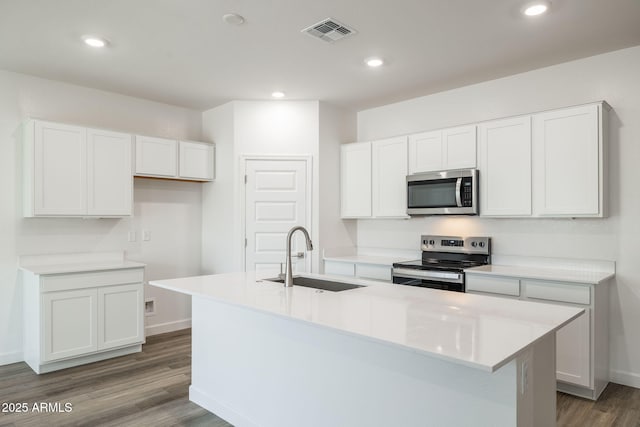 17778 W Turquoise Ave, Waddell, AZ 85355 - kitchen with stainless steel appliances, a sink, a kitchen island with sink, wood finished floors, and white cabinetry