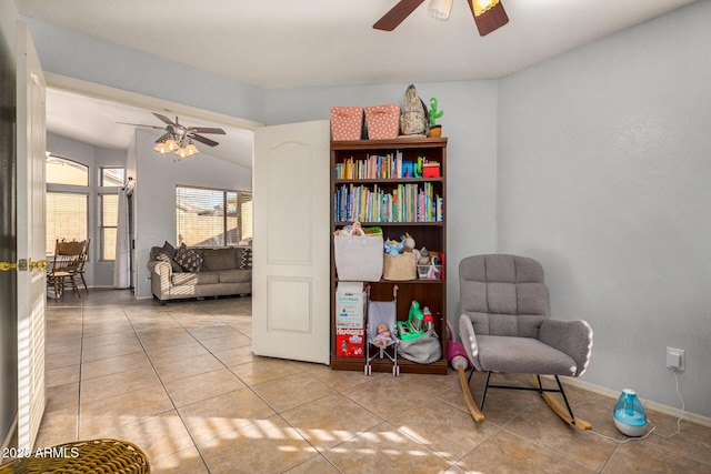 living area featuring ceiling fan, light tile patterned floors, and lofted ceiling