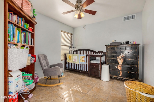 tiled bedroom featuring ceiling fan and a nursery area