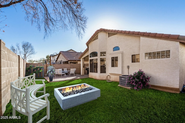 rear view of house with a fire pit, central air condition unit, a patio, and a lawn