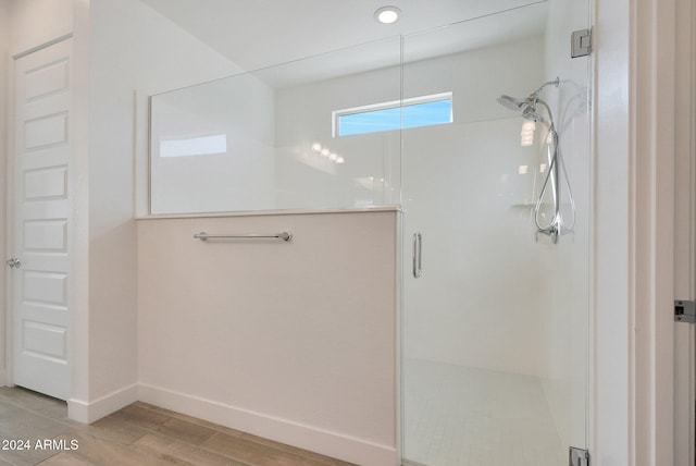 bathroom with hardwood / wood-style flooring and a shower with door