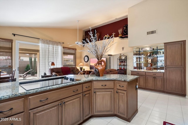 kitchen with vaulted ceiling, kitchen peninsula, ceiling fan, black electric stovetop, and light stone countertops