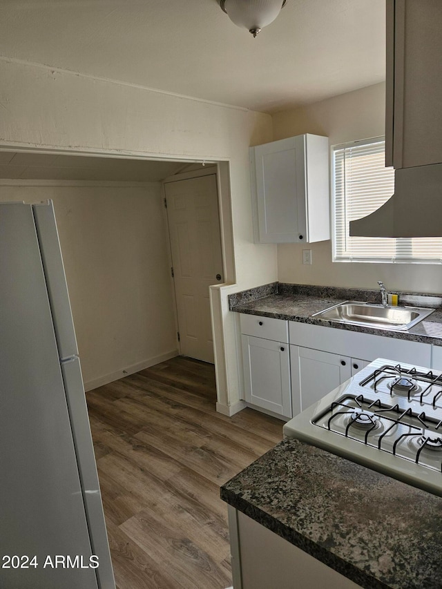 kitchen with white cabinetry, sink, stove, white fridge, and wood-type flooring