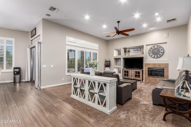 living room featuring ceiling fan, a healthy amount of sunlight, wood-type flooring, and a fireplace