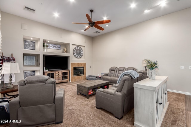 carpeted living room with a tile fireplace, ceiling fan, and built in features