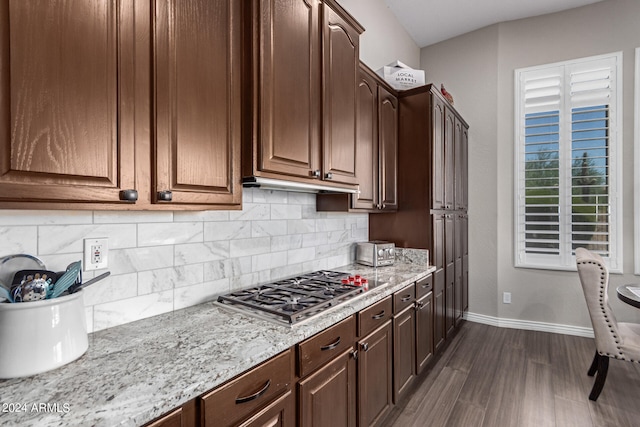 kitchen with dark brown cabinetry, backsplash, stainless steel gas stovetop, and dark wood-type flooring