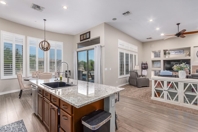 kitchen featuring decorative light fixtures, light stone counters, plenty of natural light, and sink