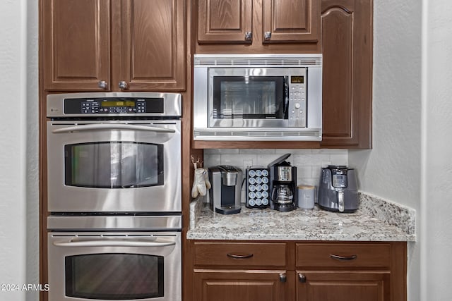 kitchen featuring tasteful backsplash, light stone counters, and stainless steel appliances