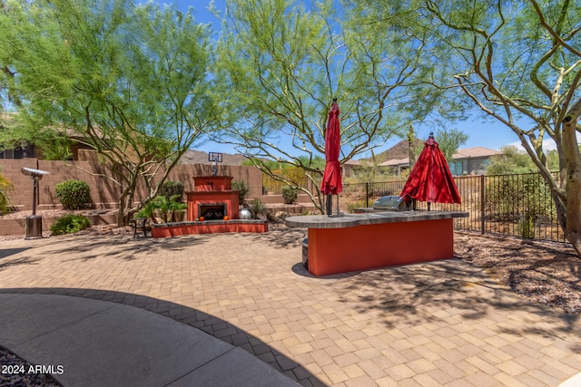 view of patio featuring an outdoor kitchen, an outdoor fireplace, and grilling area