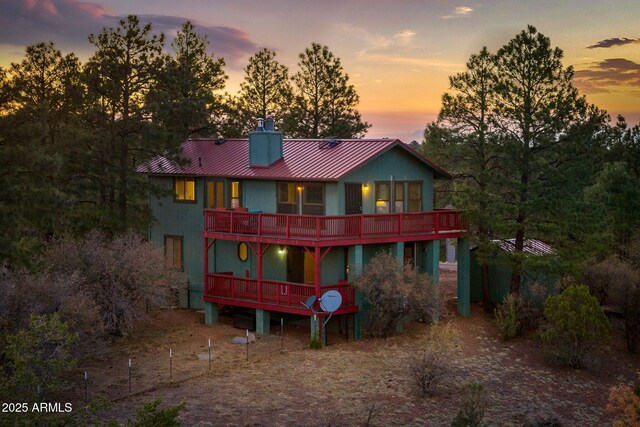 2901 Ridge Cir, Overgaard, AZ 85933 - back of property at dusk with metal roof, a wooden deck, a standing seam roof, and a chimney