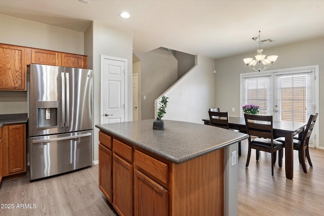 17802 N 114th Ln, Surprise, AZ 85378 - kitchen featuring stainless steel refrigerator with ice dispenser, dark countertops, light wood finished floors, brown cabinets, and a chandelier