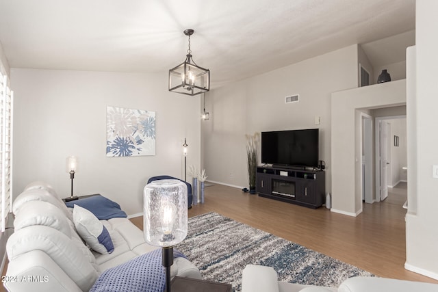 living room with a chandelier, dark hardwood / wood-style floors, and lofted ceiling