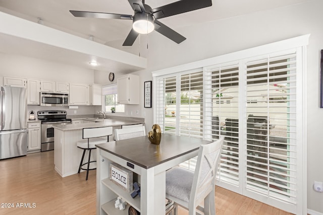 dining room with ceiling fan, light hardwood / wood-style floors, lofted ceiling, and sink