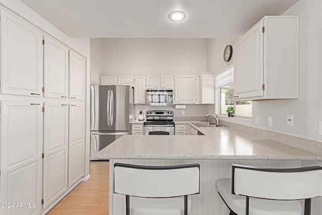 kitchen featuring white cabinets, stainless steel appliances, kitchen peninsula, and sink