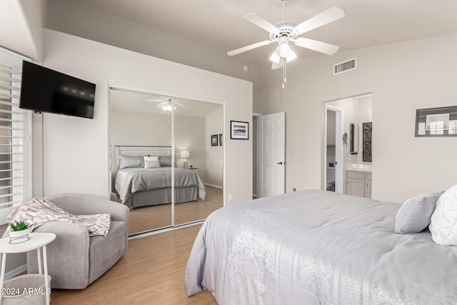 bedroom featuring ceiling fan, ensuite bathroom, light hardwood / wood-style flooring, and a closet